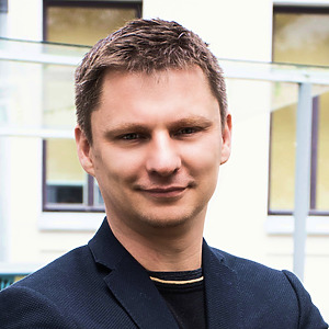 Dr. Rimantas Vosylis stovi prie pastato &scaron;viesiame fone, trumpi plaukai, &scaron;iek tiek &scaron;ypsosi, vilki tamsų &scaron;varką.